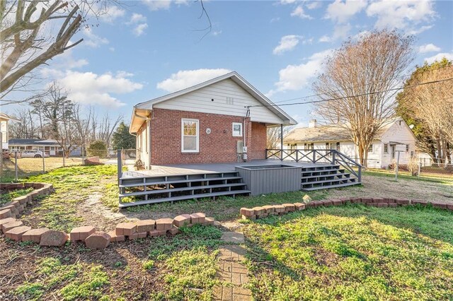 back of house with a yard, brick siding, fence, and a deck