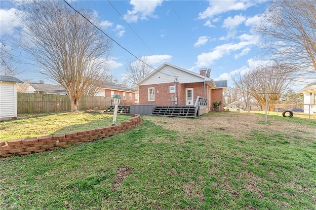 back of property featuring brick siding, a lawn, a chimney, and a fenced backyard