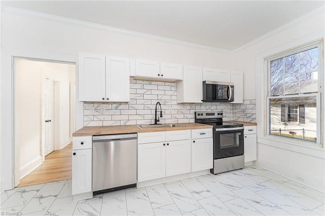 kitchen with marble finish floor, butcher block counters, appliances with stainless steel finishes, and a sink