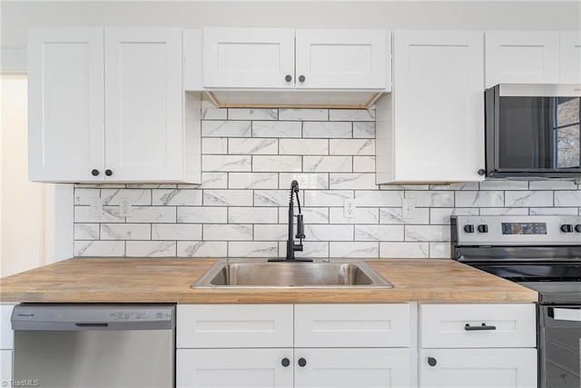 kitchen with appliances with stainless steel finishes, butcher block countertops, a sink, and backsplash