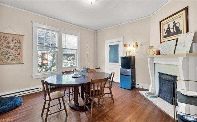 dining room featuring crown molding, a baseboard heating unit, and dark hardwood / wood-style flooring