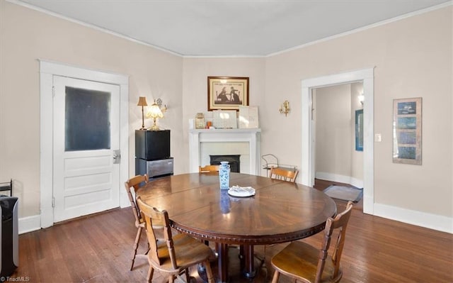 dining area with ornamental molding and dark hardwood / wood-style flooring