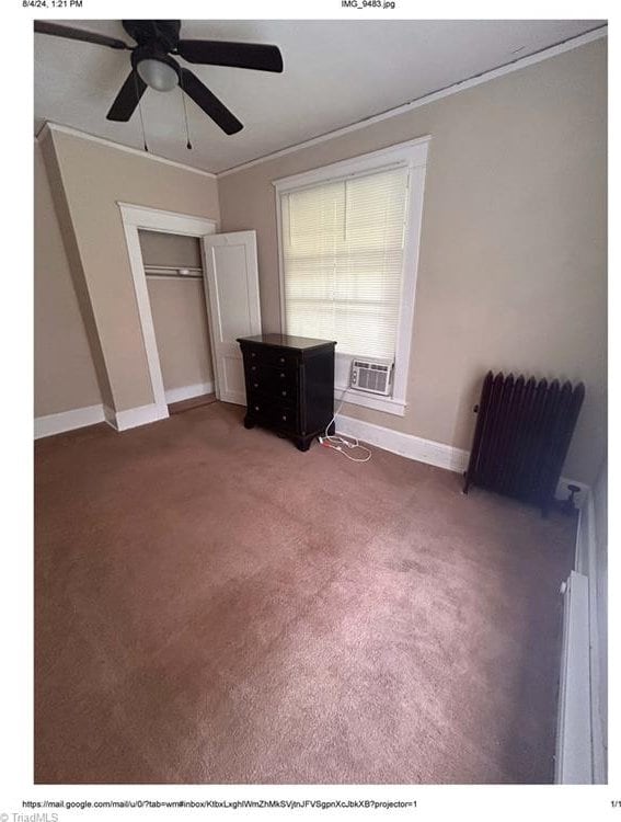 unfurnished bedroom with a closet, ceiling fan, crown molding, and dark carpet