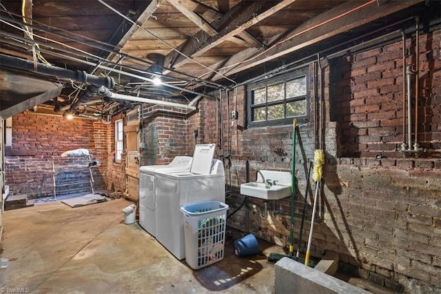 basement with brick wall, sink, and washing machine and clothes dryer