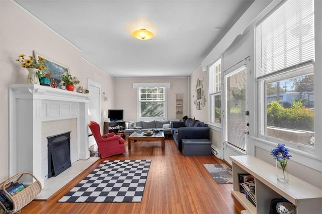 living room featuring light hardwood / wood-style flooring, ornamental molding, and a brick fireplace