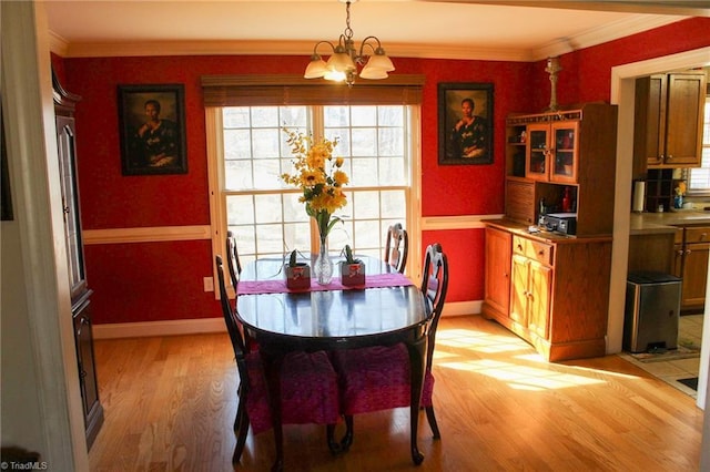 dining area featuring crown molding, light hardwood / wood-style floors, and a notable chandelier