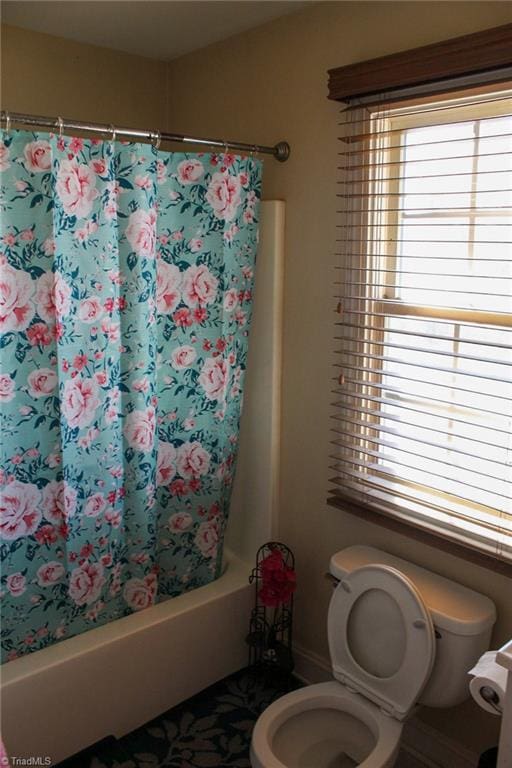 bathroom with shower / bath combination with curtain and toilet