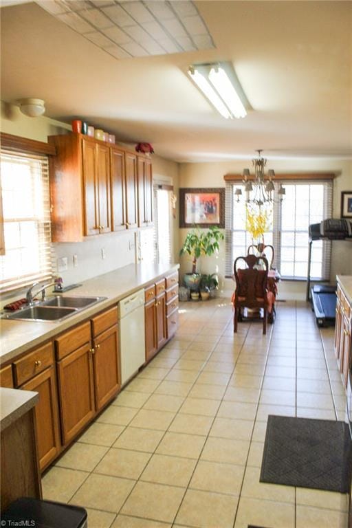 kitchen with plenty of natural light, sink, light tile patterned floors, and white dishwasher