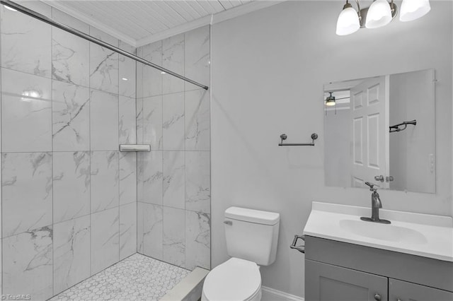 bathroom with toilet, ornamental molding, vanity, and a tile shower