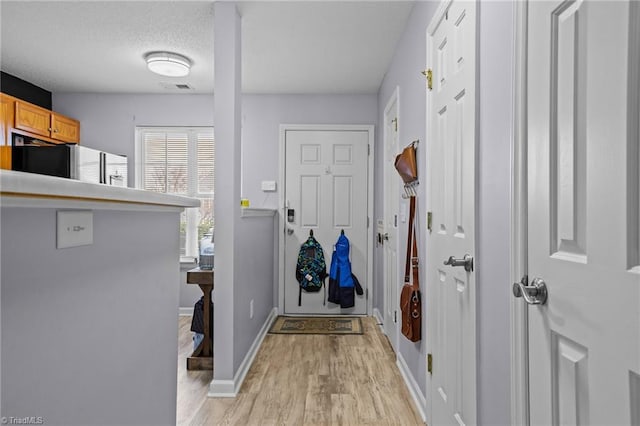 doorway with light hardwood / wood-style flooring and a textured ceiling