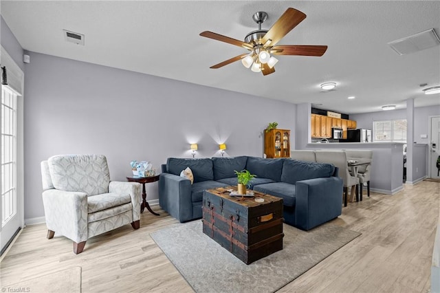 living room with light hardwood / wood-style floors and ceiling fan