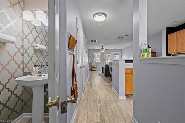 hall featuring light hardwood / wood-style floors and a textured ceiling