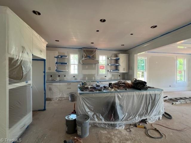 kitchen featuring white cabinets, extractor fan, stainless steel refrigerator, and wall chimney range hood