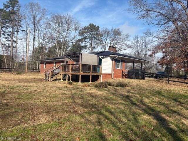 back of house featuring a lawn and a wooden deck