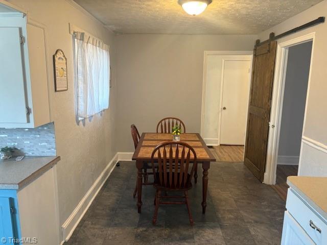 dining space with a barn door and a textured ceiling