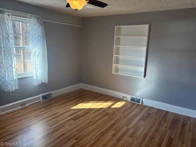 spare room featuring hardwood / wood-style flooring, ceiling fan, a healthy amount of sunlight, and a textured ceiling