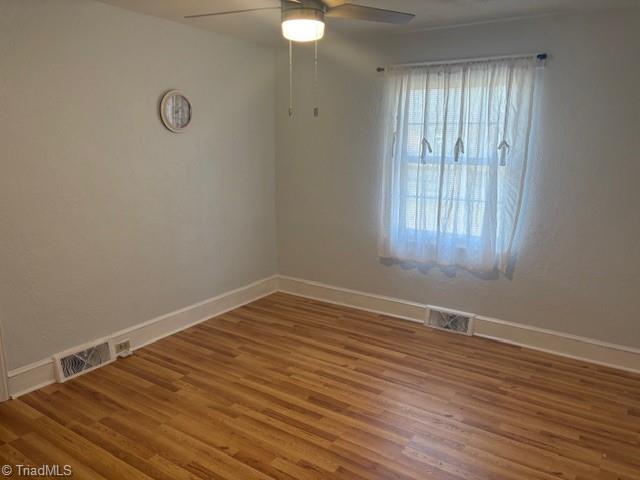 empty room with ceiling fan and wood-type flooring