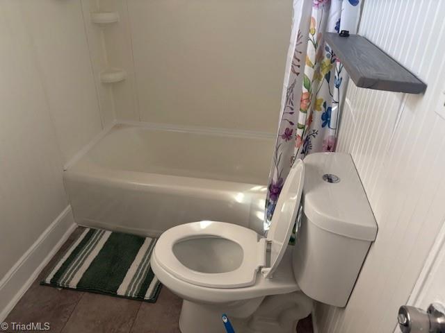 bathroom with shower / tub combo, toilet, and tile patterned floors