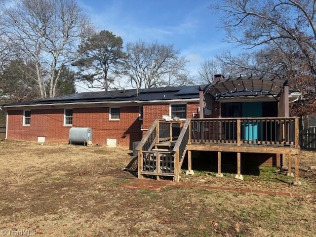 back of house featuring a pergola, a wooden deck, and solar panels