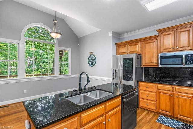 8300 Trottington Rd, Stokesdale, NC 27357 - kitchen featuring stainless steel appliances, brown cabinetry, light wood-type flooring, an island with sink, and vaulted ceiling