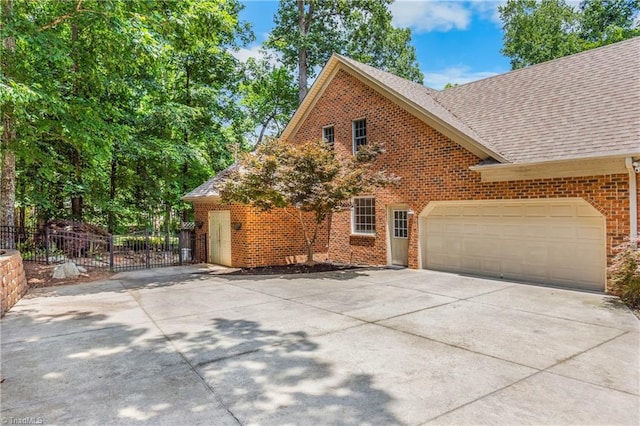 8300 Trottington Rd, Stokesdale, NC 27357 - view of side of property featuring driveway, brick siding, a shingled roof, and a garage