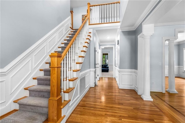 8300 Trottington Rd, Stokesdale, NC 27357 - stairway featuring ornate columns, wood finished floors, ornamental molding, a decorative wall, and wainscoting