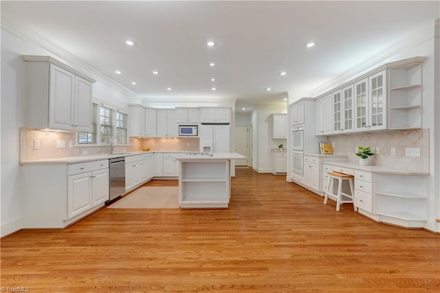 kitchen with a center island, light wood-type flooring, white appliances, white cabinets, and ornamental molding