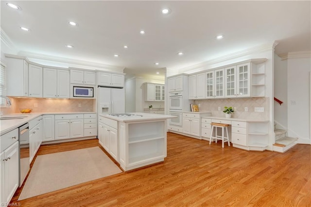 kitchen with ornamental molding, white appliances, light hardwood / wood-style flooring, white cabinets, and a center island