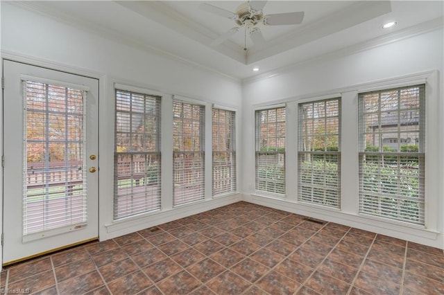 unfurnished sunroom with a tray ceiling, ceiling fan, and a healthy amount of sunlight