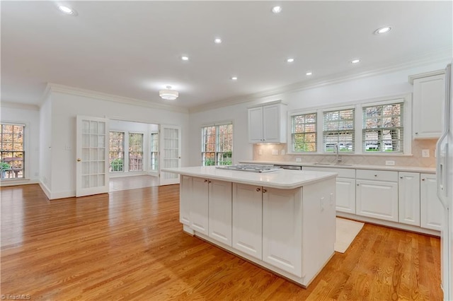 kitchen featuring decorative backsplash, light hardwood / wood-style floors, white cabinetry, and a kitchen island