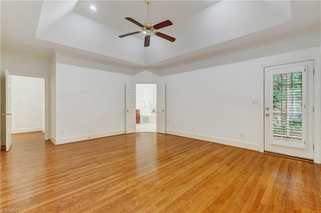 unfurnished room with ceiling fan, light hardwood / wood-style floors, and a raised ceiling