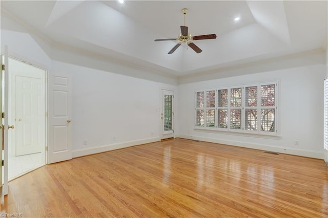 unfurnished room with light hardwood / wood-style floors, a raised ceiling, and ceiling fan