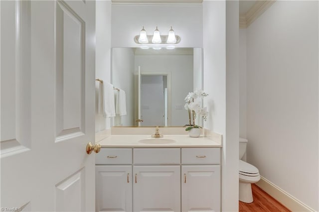 bathroom with hardwood / wood-style floors, vanity, ornamental molding, and toilet