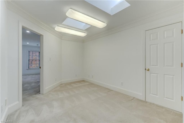 spare room featuring a skylight, light colored carpet, and ornamental molding