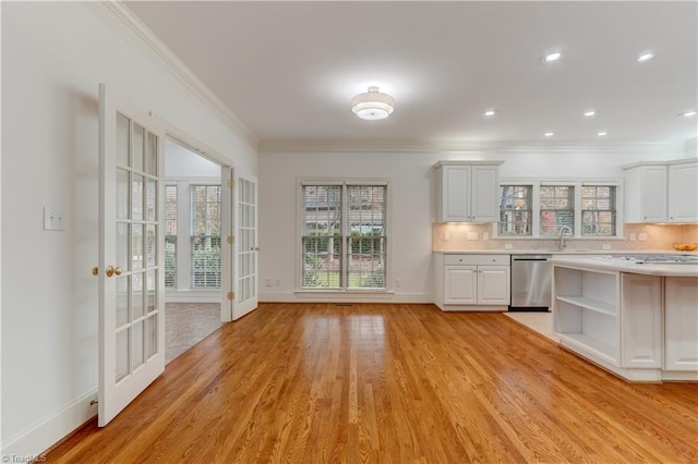 kitchen with crown molding, dishwasher, white cabinets, and light wood-type flooring