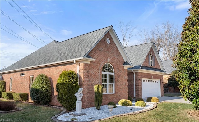 view of side of property featuring an attached garage, brick siding, driveway, roof with shingles, and a lawn