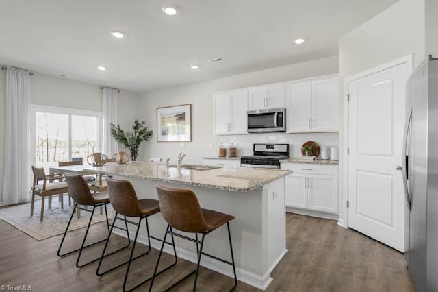 kitchen with stainless steel appliances, sink, a center island with sink, and white cabinets