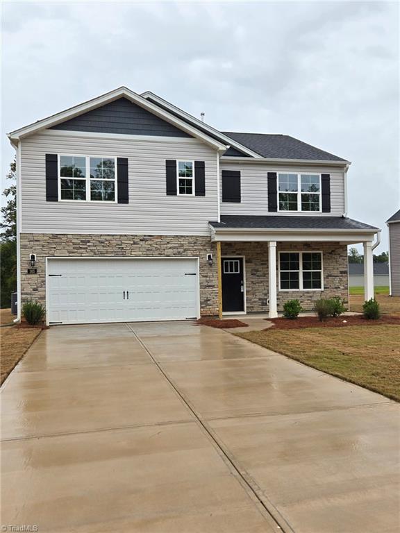 view of front of property featuring a garage, a porch, and a front lawn