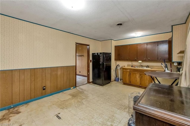 kitchen featuring black refrigerator, a textured ceiling, and sink