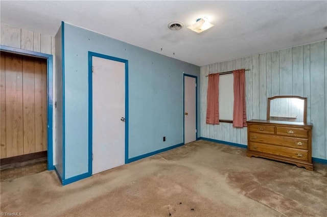 unfurnished bedroom featuring carpet flooring, a closet, and wooden walls