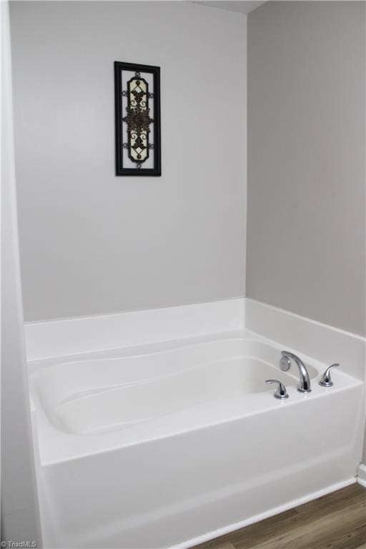 bathroom with a bath and wood finished floors