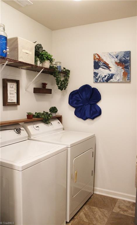 clothes washing area with baseboards, laundry area, and washing machine and clothes dryer