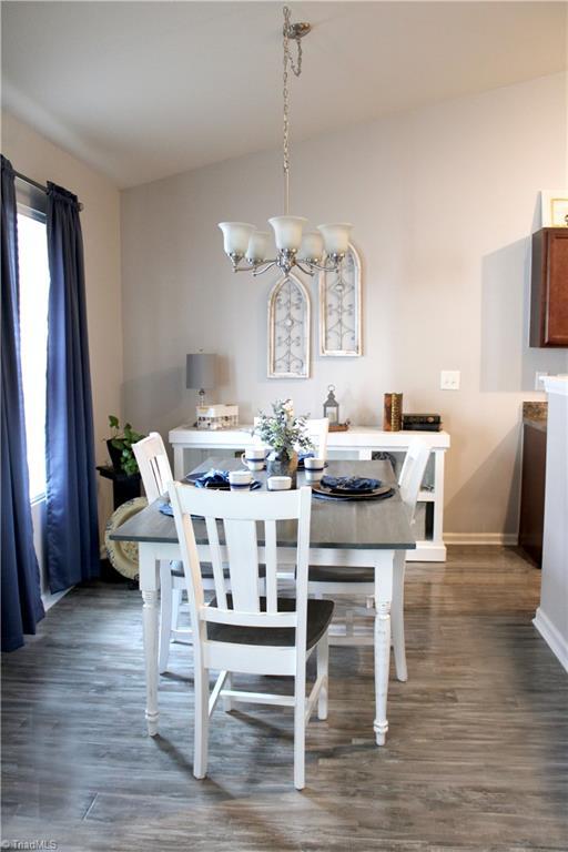 dining room featuring baseboards, an inviting chandelier, and dark wood-style flooring