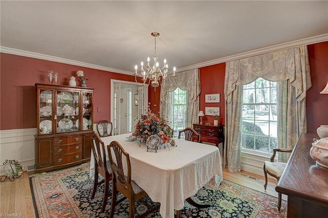 dining space featuring an inviting chandelier, crown molding, and light wood-style floors