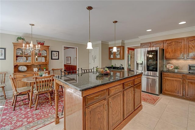 kitchen with hanging light fixtures, stainless steel fridge with ice dispenser, light tile patterned floors, ornamental molding, and glass insert cabinets