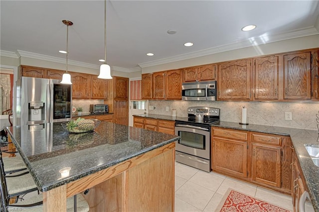 kitchen featuring brown cabinets, crown molding, appliances with stainless steel finishes, and dark stone countertops