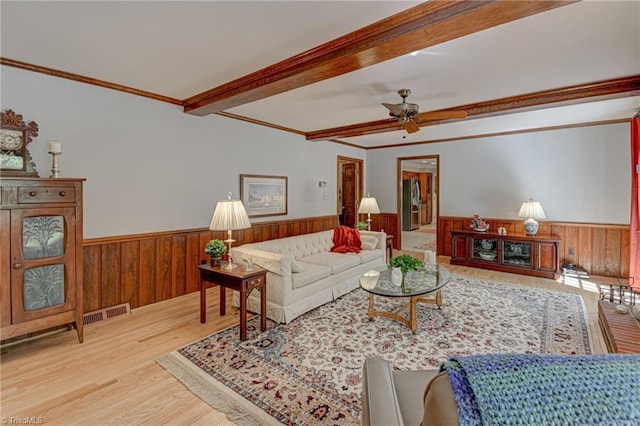 living room featuring wooden walls, ornamental molding, wainscoting, and wood finished floors