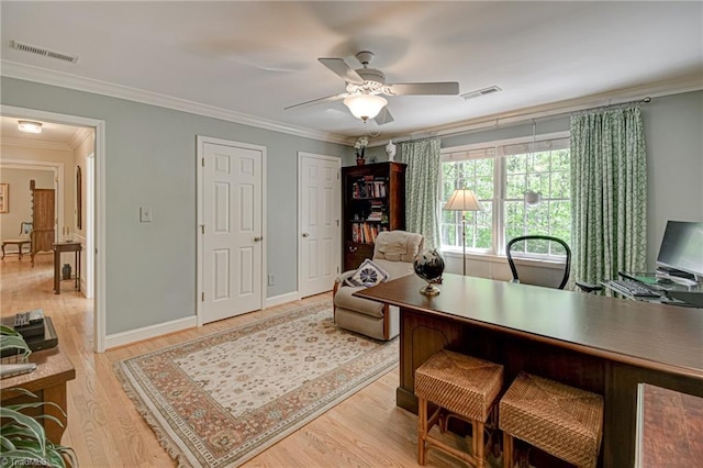 office space featuring crown molding, a ceiling fan, visible vents, and light wood-style floors