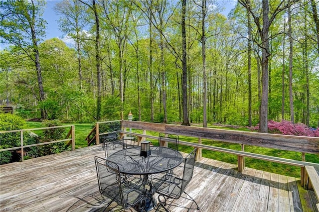 deck featuring outdoor dining area and a view of trees
