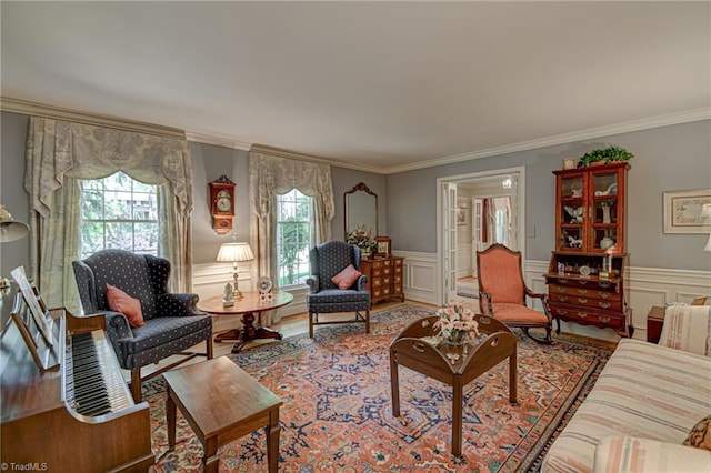 living area featuring crown molding, wood finished floors, a decorative wall, and a wainscoted wall